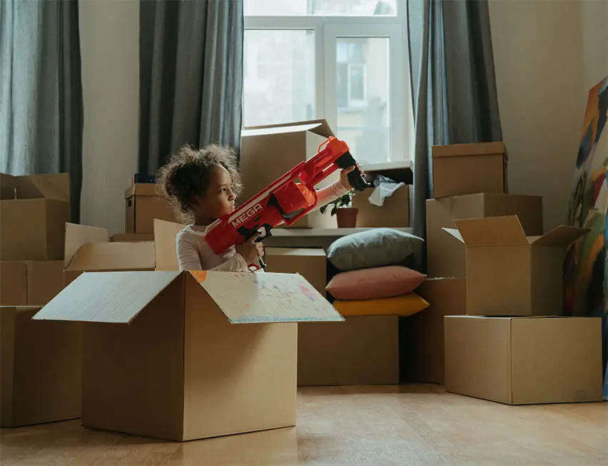 Enfant dans un carton avec un fusil NERF